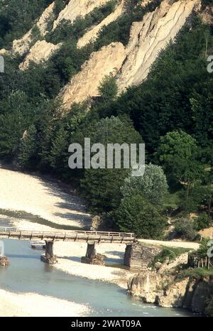Contea di Vrancea, Romania, circa 1977. Vista della valle del fiume Putna, con il vecchio ponte di legno che porta al villaggio di Poduri. Foto Stock