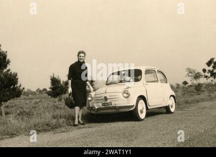 Donna vestita di nero e auto FIAT 600 per strada, Roma, Italia anni '1960 Foto Stock