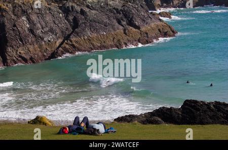 Body Boarders in attesa della grande onda a Kynance Cove, Cornovaglia. Visitatori disinteressati a fine campo. Foto Stock