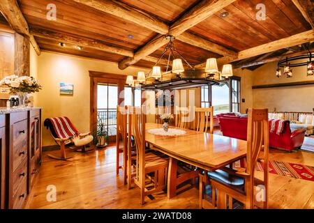 Una sala da pranzo aperta e ariosa con grandi finestre lungo le pareti e sedie riunite intorno a un tavolo Foto Stock
