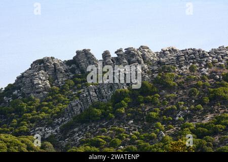 Una ripida montagna rocciosa e scogliere arroccate sul Mar Egeo, sulla costa meridionale dell'isola greca di Ikaria, vicino a Karkinagri, Grecia. Foto Stock