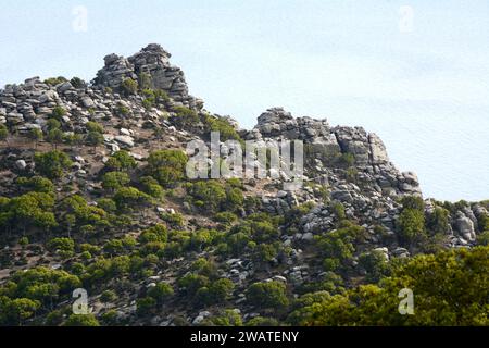 Una ripida montagna rocciosa e scogliere arroccate sul Mar Egeo, sulla costa meridionale dell'isola greca di Ikaria, vicino a Karkinagri, Grecia. Foto Stock