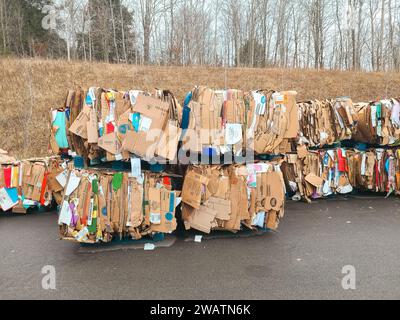 Le scatole di cartone rotte sono appiattite e impilate per essere riciclate e inviate al camion di riciclaggio dietro il grande magazzino Foto Stock