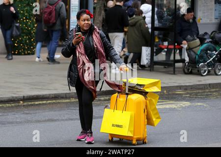 Londra, Regno Unito. 16 dicembre 2023. Un acquirente con un certo numero di borse per lo shopping di Selfridges cammina su Oxford Street nel centro di Londra all'inizio delle vendite invernali. (Foto di Steve Taylor/SOPA Images/Sipa USA) credito: SIPA USA/Alamy Live News Foto Stock