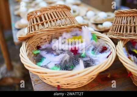 Piume colorate in un cestino di vimini. Artigianato di Pasqua fai da te Foto Stock