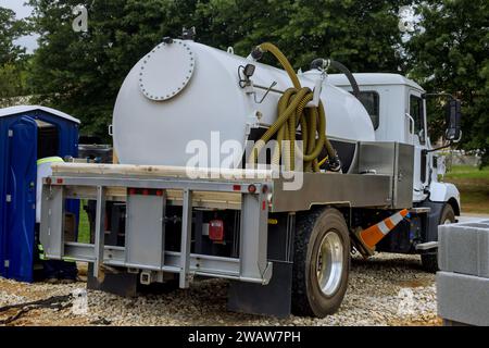 Utilizzo di un carrello settico per pulire i servizi igienici portatili in cantiere Foto Stock