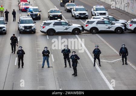 Seattle, Washington, USA. 6 gennaio 2024. I membri del dipartimento di polizia di Seattle si schierano mentre i manifestanti bloccano la i-5 in direzione nord in solidarietà con la Palestina. Le proteste settimanali che chiedono un cessate il fuoco immediato sono aumentate dallo scoppio della guerra tra Israele e gruppi militanti palestinesi guidati da Hamas nella Striscia di Gaza in ottobre. Credito: Paul Christian Gordon/Alamy Live News Foto Stock