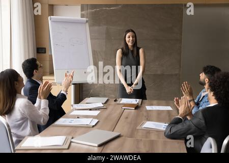 Team aziendale eterogeneo entusiasta applaudendo a un project manager felice e di successo Foto Stock