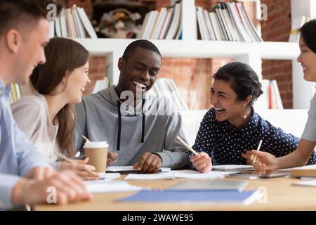 Sorridenti studenti multietnici ridono studiando insieme in classe Foto Stock