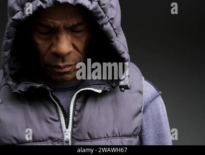 Pregare dio per il perdono l'uomo caraibico che prega con sfondo grigio nero con la gente stock immagine foto stock Foto Stock