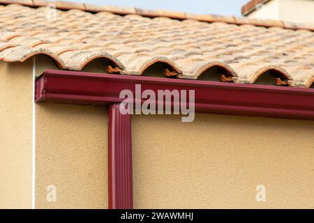Tetto con grondaie rosse grondaie in alluminio e piumino sulla nuova facciata della casa Foto Stock