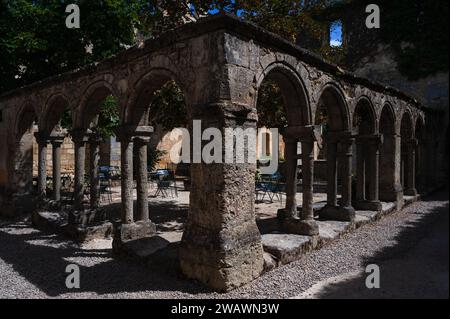 Il Chiostro dei Cordelieri o le Cloître des Cordeliers a Saint-Emilion, borgo medievale nel cuore della zona vinicola di Bordeaux nel dipartimento della Gironda, Nouvelle-Aquitaine, Francia. Oggi ci sono tavoli e sedie nell'ex giardino del monastero, dove i visitatori possono gustare vino frizzante, il Crémant de Bordeaux, dalle cantine sottostanti. Foto Stock