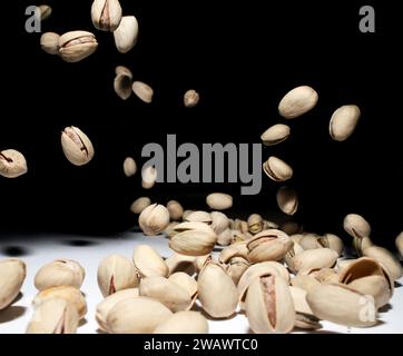 Dadi di pistacchio che cadono. A mezz'aria su sfondo scuro. Tempo congelato. Base di dieta sana. Foto Stock