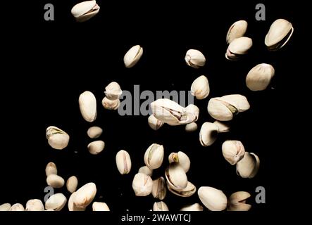 Dadi di pistacchio che cadono. A mezz'aria su sfondo scuro. Tempo congelato. Base di dieta sana. Foto Stock