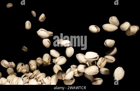 Dadi di pistacchio che cadono. A mezz'aria su sfondo scuro. Tempo congelato. Base di dieta sana. Foto Stock