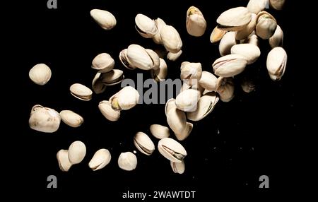 Dadi di pistacchio che cadono. A mezz'aria su sfondo scuro. Tempo congelato. Base di dieta sana. Foto Stock