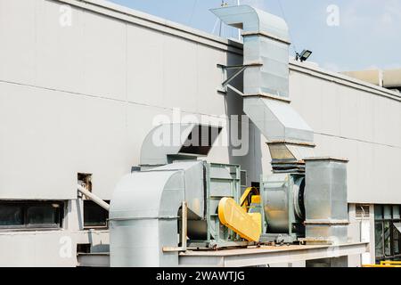 Sistema di ventilazione dell'aria in un grande edificio commerciale, ventilatore a flusso d'aria con condotto del filtro antifumo all'esterno dell'edificio del tetto. Foto Stock