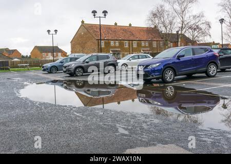 Grande pozzanghera nel parcheggio di un supermercato a seguito della pioggia battente. Foto Stock