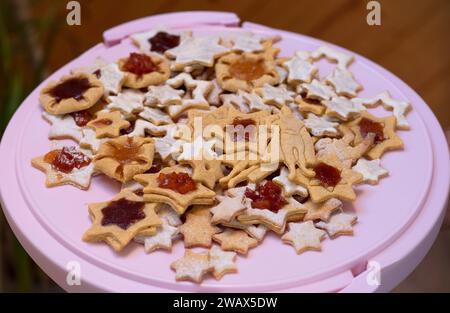 Un mucchio di stelle al forno e supereroi, biscotti fatti a mano su un piedistallo rosa Foto Stock