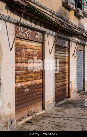 Un vicolo con negozi deserti, protetto da clienti non invitati con tende arrugginite. Foto Stock