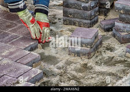 lavoratore che posa lastre di pavimentazione per strada Foto Stock