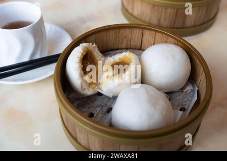 Dim sum cantonese - lin yong (o yung) bao Buns ripieni di pasta di semi di loto - serviti in una vaporiera di bambù con tè oolong in accompagnamento, Regno Unito Foto Stock