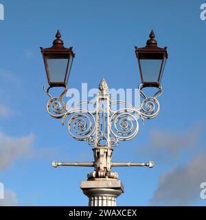 Una lampada a doppio periodo, il dettaglio della testa da una colonna di illuminazione con lavorazioni metalliche ornate a scorrimento Foto Stock