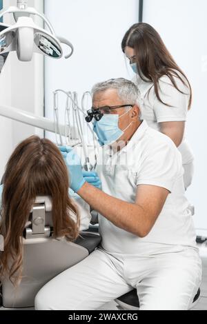 Il dentista lavora in una clinica moderna e luminosa, creando un ambiente piacevole per il trattamento. Pulizia e ordine sono i suoi principi di base. Foto Stock