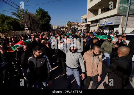 Jenin. 7 gennaio 2024. La gente partecipa al funerale di una vittima nella città di Jenin, in Cisgiordania, il 7 gennaio 2024. Sette palestinesi sono stati uccisi domenica mattina da un drone israeliano nella Cisgiordania occupata, mentre un agente di polizia israeliano è stato ucciso quando il suo veicolo ha colpito una bomba a bordo strada, hanno dichiarato fonti israeliane e palestinesi domenica. Il Ministero della salute palestinese ha dichiarato in una dichiarazione che le sette vittime erano civili, tra cui quattro fratelli del villaggio di Muthalath ash-Shuhada, nella zona di Jenin, nella Cisgiordania settentrionale. Credito: Ayman Nobani/Xinhua/Alamy Live News Foto Stock