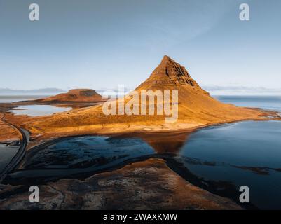 Splendida vista aerea dell'alta montagna Kirkjufell in Islanda, sulla penisola di Snaefellsnes. Alba al tramonto con luce arancione tenue. Islanda occidentale. Foto Stock