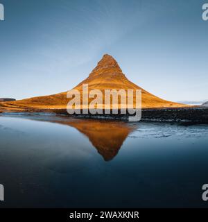 Splendida vista aerea dell'alta montagna Kirkjufell in Islanda, sulla penisola di Snaefellsnes. Alba al tramonto con luce arancione tenue. Islanda occidentale. Foto Stock