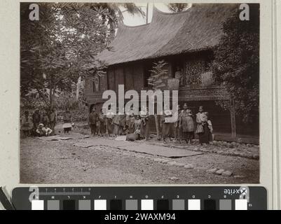 Ritratto di gruppo di donne e bambini sconosciuti per una casa di minankabauer, 1891 - 1912 foto di carta albumen stampare anonime persone storiche ritratte in un gruppo, in un ritratto di gruppo. esterno  rappresentazione di un edificio Foto Stock