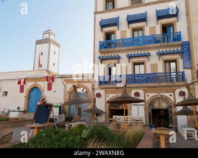 Hotel e ristorante con balconi e porte blu e giardino accanto a una torre nella storica medina nella città di Essaouira, Marocco. 7 gennaio 2024 Foto Stock