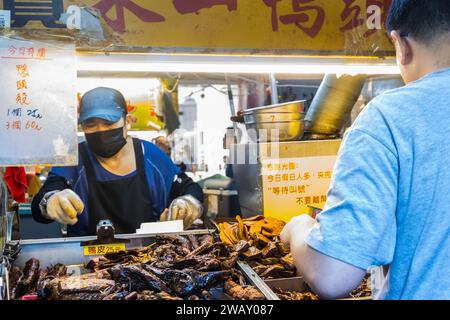 Taipei, Taiwan - 9 ottobre 2023: Venditori ambulanti che vendono cucine taiwanesi e cibo di mare al mercato notturno di Raohe a Taiwan Foto Stock