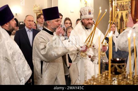 Novo-Ogaryovo, Russia. 7 gennaio 2024. L'Arcivescovo ortodosso russo Nikolay Mosolov, giusto, accende le candele durante una messa natalizia con il presidente Vladimir Putin nella chiesa dell'icona del Salvatore non fatta a mano nel complesso della residenza presidenziale ufficiale, il 7 gennaio 2024 a Novo-Ogaryovo, Oblast' di Mosca, Russia. Putin ha ospitato famiglie di soldati uccisi nella guerra Ucraina per la celebrazione. Crediti: Gavriil Grigorov/Cremlino Pool/Alamy Live News Foto Stock