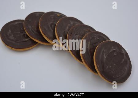 Deliziosi biscotti rotondi con marmellata naturale ricoperti di cioccolato naturale su sfondo bianco. Foto Stock