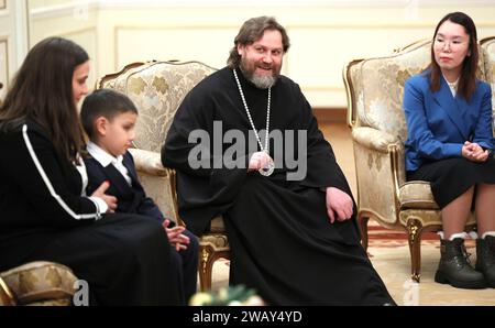 Novo-Ogaryovo, Russia. 7 gennaio 2024. L'arcivescovo ortodosso russo Nikolay Mosolov, centro, incontra le famiglie militari in seguito alle celebrazioni ortodosse di Natale ospitate dal presidente Vladimir Putin presso il complesso presidenziale ufficiale, il 7 gennaio 2024 a Novo-Ogaryovo, Oblast' di Mosca, Russia. Putin ha ospitato famiglie di soldati uccisi nella guerra Ucraina per la celebrazione. Crediti: Gavriil Grigorov/Cremlino Pool/Alamy Live News Foto Stock