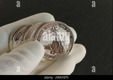 Monete d'argento nelle mani di un numismatico. Due sterline Britannia. Foto Stock