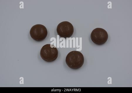 Cioccolatini, arachidi, noci, uva passa ricoperta di glassa al cioccolato, ciottoli di cioccolato disposti su sfondo bianco. Foto Stock