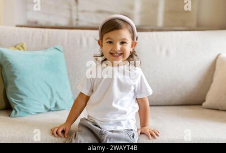 Una bambina felice, in età prescolare, comodamente seduto sul divano a casa Foto Stock