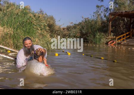 Il sacerdote cristiano batte la donna nelle acque del fiume Giordano al confine tra Palestina e Giordania a Qasr al-Yahud, sito battesimale di Gesù Cristo Foto Stock