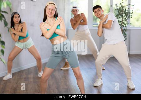 Adolescenti normali e ragazzi che eseguono il movimento del passo di calcio durante l'allenamento insieme in studio di danza Foto Stock