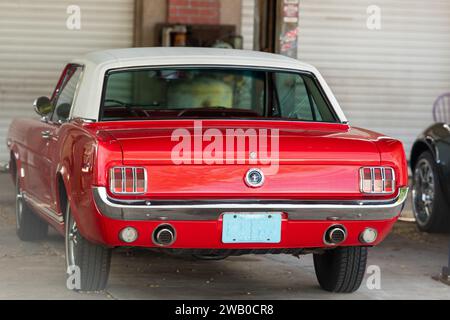 Orlando, Florida, Stati Uniti - 1° gennaio 2024: Una vivace muscle car color rosso mela, la Ford Mustang del 1965, è parcheggiata in un garage. Foto Stock