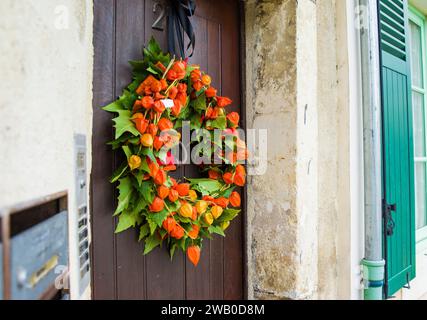 Corona autunnale con Physalis su una porta di legno Foto Stock