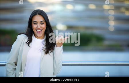 Allegra donna d'affari araba che punta il pollice da parte al Copy Space Outdoors Foto Stock