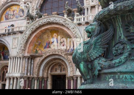 Antico ornamento di strada con leoni alati e basilica di San Marco sullo sfondo, in San Piazza Marco, famosa attrazione turistica a Venezia, Italia. Foto Stock