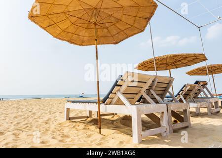 ombrelloni da spiaggia colorati in legno e lettini sdraio sulla spiaggia sabbiosa dell'oceano Foto Stock