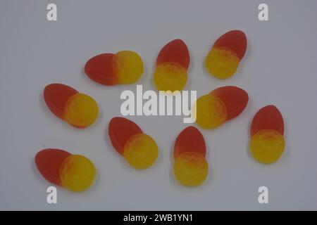 Caramelle gommose per bambini di marca, fabbricate in fabbrica, sotto forma di piccoli frutti, mirtilli, bacche gialle disposte su sfondo bianco. Foto Stock