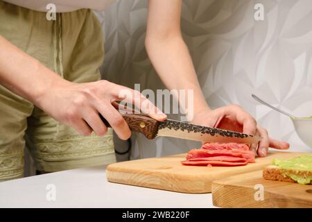 Vista ravvicinata delle mani femminili che tagliano il salmone affumicato Foto Stock