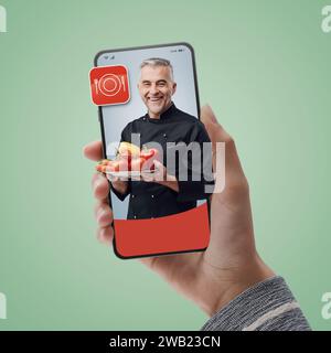 Chef sorridente sullo schermo dello smartphone: Assumi professionisti online e cucina su richiesta Foto Stock